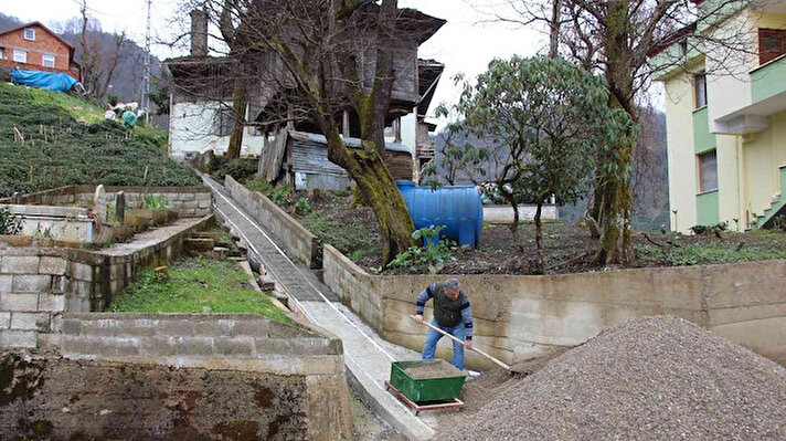 ​Trabzon'da ev yapacağı araziye yol gitmediği için 55 metre uzunluğundaki patika yola ray döşeyen Mehmet Hacıefendioğlu, inşaat malzemelerini teleferik yardımıyla bu yolla taşıyor.