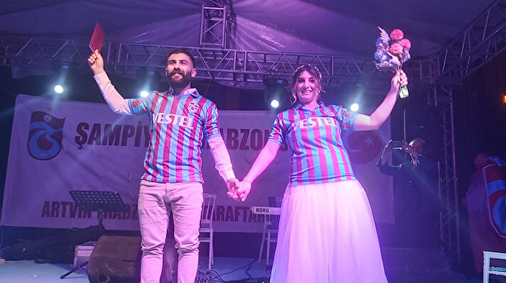 Artvin'de, Trabzonspor'un şampiyonluk kutlamaları kapsamında düzenlenen etkinliğe katılan nişanlı çiftin nikahı kıyıldı.<br><br>Artvin Trabzonspor Taraftarlar Derneği, bordo-mavili takımın Spor Toto Süper Lig şampiyonluğunu kutlamak üzere Artvin Valiliği önündeki alanda etkinlik düzenledi.<br><br>Yöresel sanatçıların sahne aldığı etkinliğe katılanlar, halay çekip horon oynayarak takımlarının başarısını kutladı.