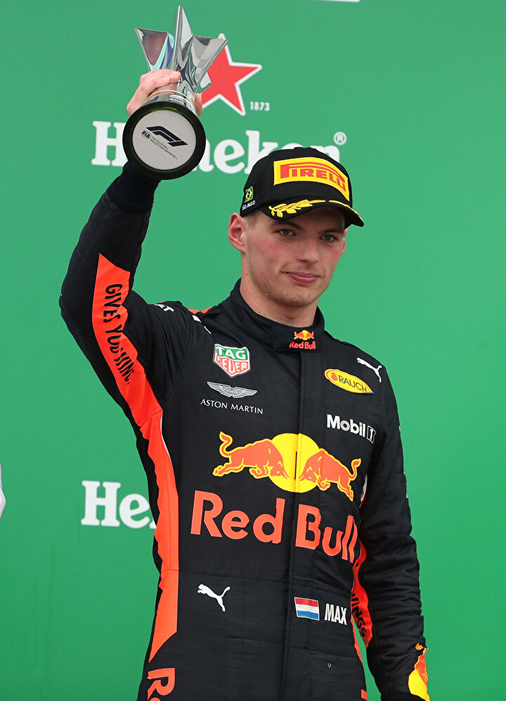 Max Verstappen, podyumda ödülü ile birlikte poz veriyor.