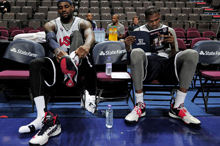 LeBron James ve Kevin Duran All-Star formasıyla benchte okuma yapıyor.