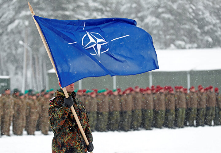 Bir asker, Alman birliklerinin ziyareti sırasında NATO bayrağını taşıyor.