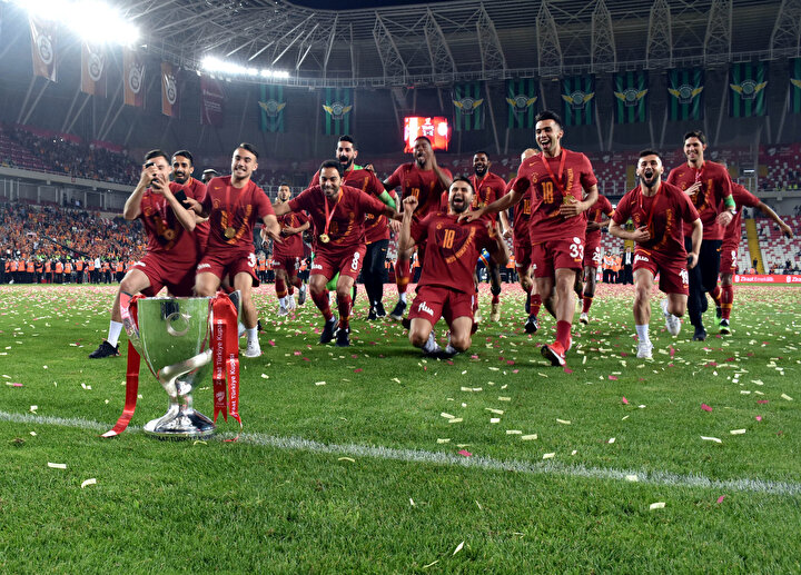 Galatasaraylı futbolcular kupaya kayarak poz vermeye hazırlanıyorlar.