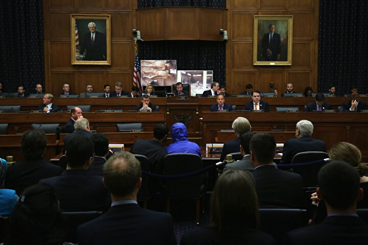 Sezar olarak bilinen eski bir Suriyeli askerî polis memuru (mavi kapüşonlu, ceketli kişi), 2014 yılında Washington’da Kongre brifinginde. (Görsel: Alex Wong/Getty Images)