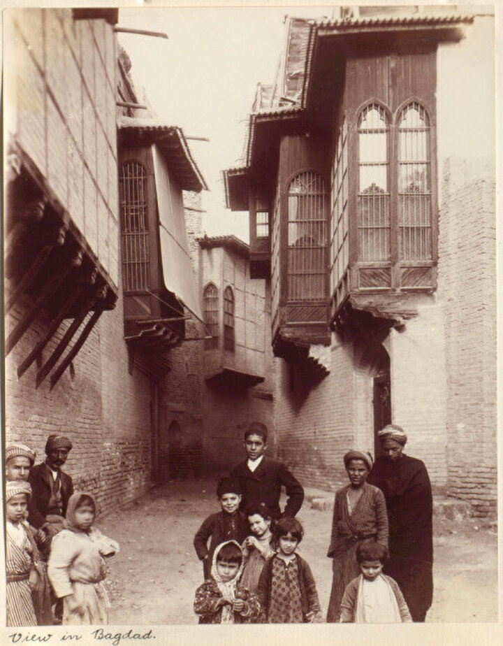 Wilfrid Malleson tarafından çekilen fotoğrafta Bağdat'ın dar sokaklarında farklı kültürlerden gelen yetişkinler ve çocuklar görülüyor, 1906.