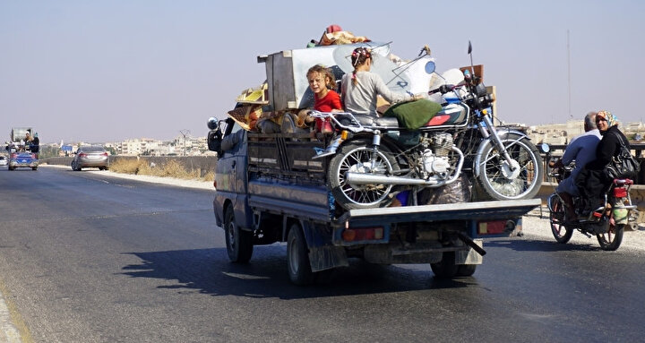 Yanlarına alabildikleri eşyalarla daha güvenli bölgelere göç etmek için yollara düşen Suriyeli bir aile.