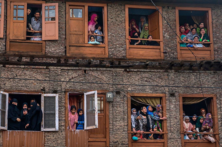 Cenaze törenine halkın katılımına polisin sınır koyduğu Keşmir'de insanlar cenaze merasimini camdan seyrediyor.
