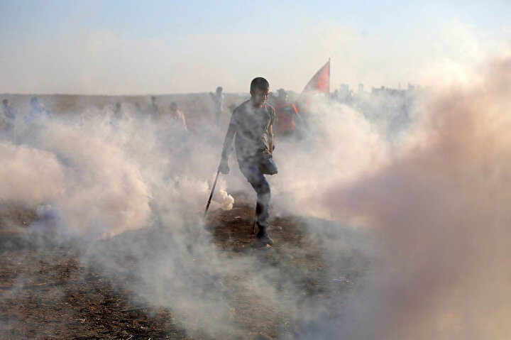 Ampute bir Filistinli Gazze Şerinde düzenlenen protesto sırasında göz yaşartıcı gazdan kaçmaya çalışıyor. Filistin Sağlık Bakanlığı'na göre, 2018 yılında İsrail saldırılarında alt uzuvlarından yaralan binlerce kişi var.