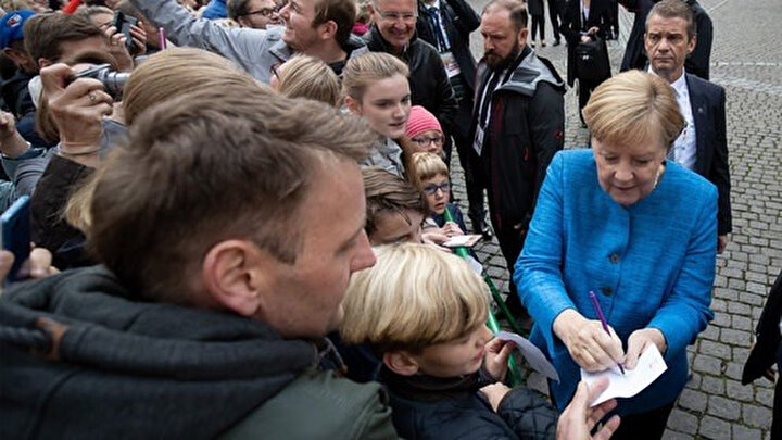 Şansölye Merkel, tören alanındaki bazı sevenlerine imza verdi.