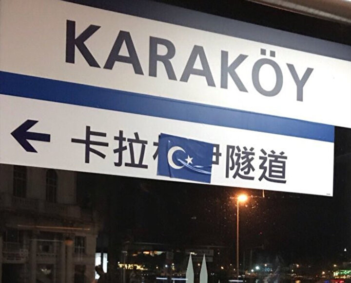 Çince yönlendirme tabelasının üstüne Doğu Türkistan bayrağı yapıştırıldı.