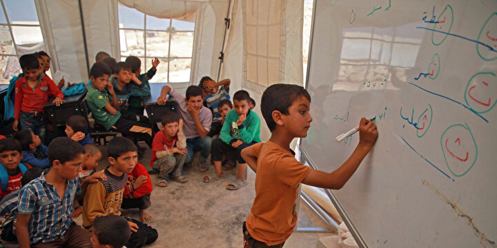 Suriyeli bir çocuk, 10 Eylül 2019'da Suriye'nin kuzeybatısındaki El-Dana kasabası yakınlarındaki bir kampta okula dönüştürülen bir UNICEF çadırında tahtada yazı yazıyor.