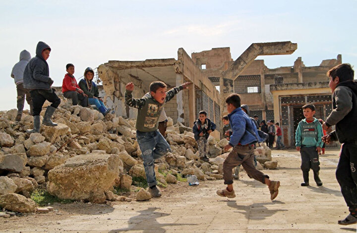 4 Şubat 2019'da çekilen bu fotoğrafta çocuklar, Suriye'nin İdlib kentine bağlı Kufayr köyünde, çatışmalara sırasında kısmen tahrip olmuş bir okulun bahçesinde oynuyorlar.