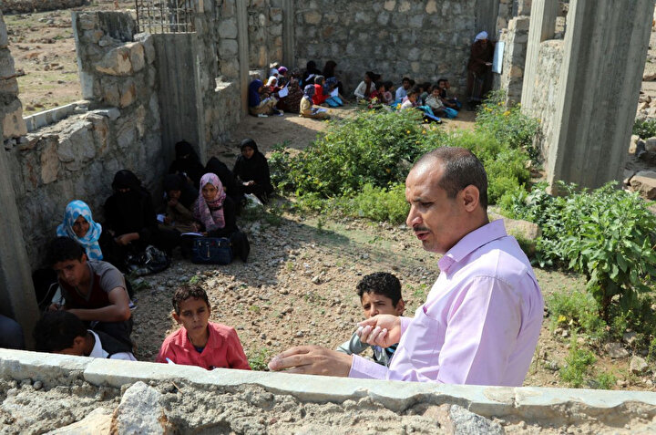 Yemenli bir öğretmen, 16 Eylül 2019'da eğitim öğretim yılının başlangıcında Taiz vilayetine bağlı bir köyde henüz inşaatı bitmemiş okulda üstü açık sınıflarda ders anlatıyor.