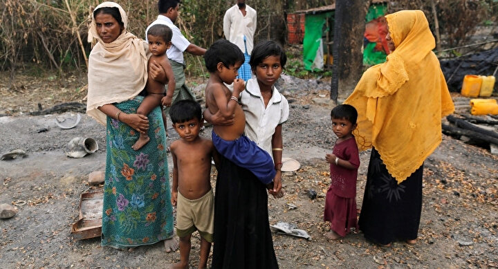 2016 yılında çekilen bu fotoğrafta, Myanmar'da yaşayan Arakanlı Müslümanlar köylerinde ateşe verilen bakkalın yanında dururken görülüyor.