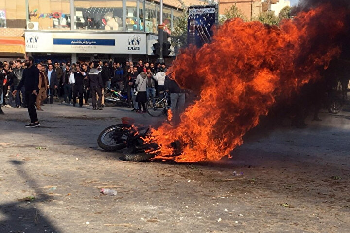 Benzin zammı protestoları sırasında İran sokaklarında ateşe verilen bir motosiklet.