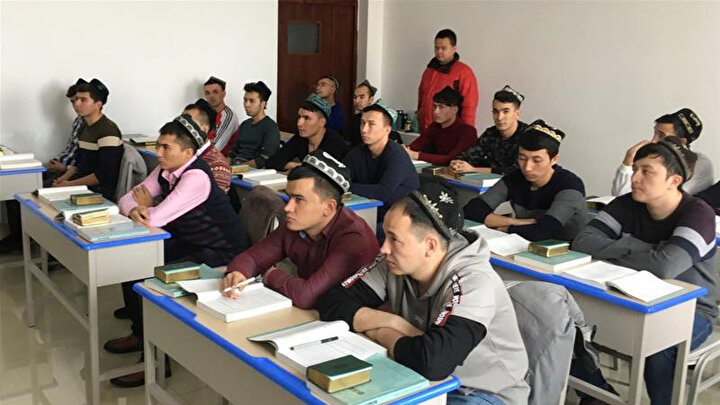 Çin'in eğitim kamplarında rızaları dışında tutularak eğitim verilen Uygurlar.