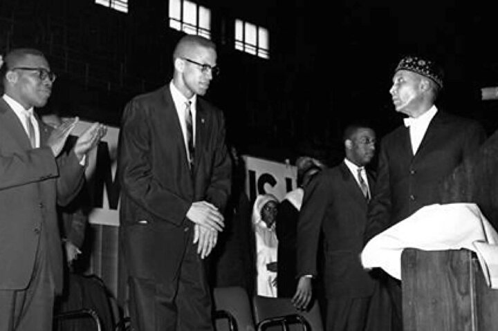 Malcolm X, Elijah Muhammed (sağda, takkeli olan) ile birlikte.