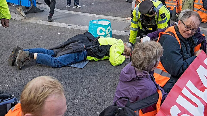 İngilterede ilginç protesto: Çevreciler yüzünü yapıştırıcıyla asfalta yapıştırdı