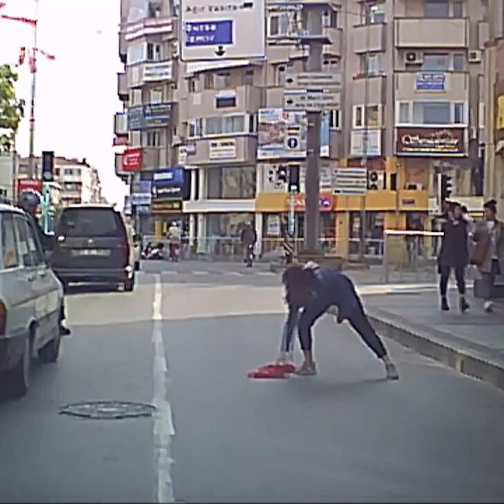 Yola düşen bayrağı araçlar üstünden geçmesin diye aldı