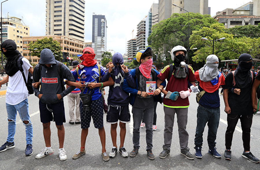 Başkent Caracas'taki protestolarda kol kola giren göstericiler.