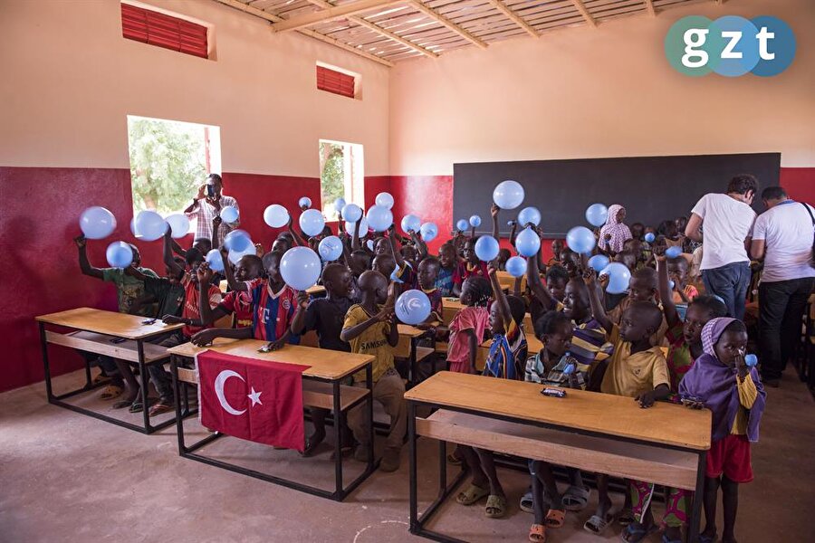 Tebessüm eden Afrikalı çocuklar yapılan derslikte eğitim alıyor.