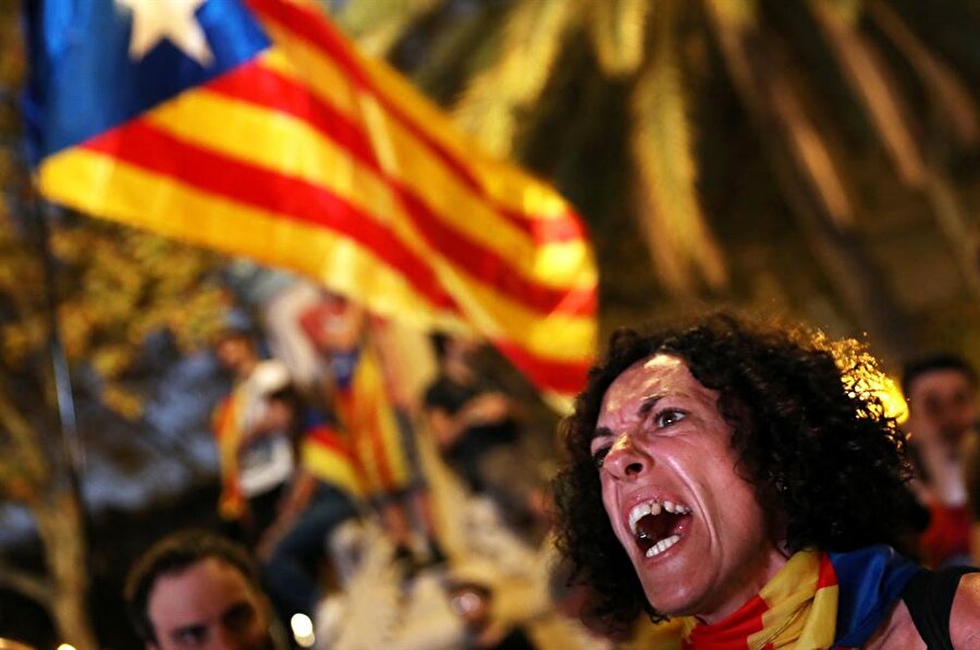 Bir kadın, Barselona'daki bağımsızlık yanlısı bir mitingde dev bir ekranda Katalon bölge parlamentosu oturumunu izlerken tepki gösteriyor.