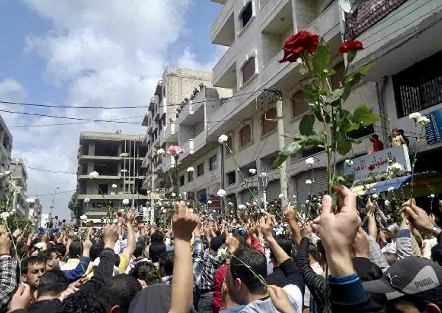 Olayların başında Suriyeliler, ellerinde çiçeklerle yürüyüşler düzenliyordu.