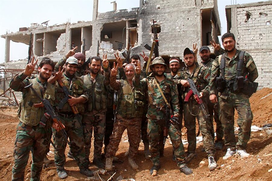 Enkaz arasında zafer işareti yapan Suriyeli askerler. (Reuters / SANA)