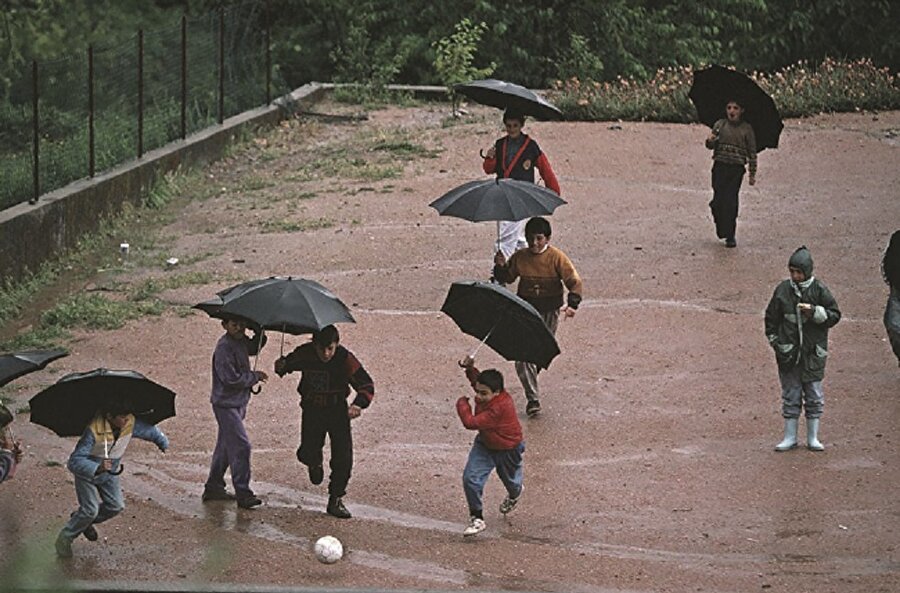 Yağmurda top oynayan çocuklar.