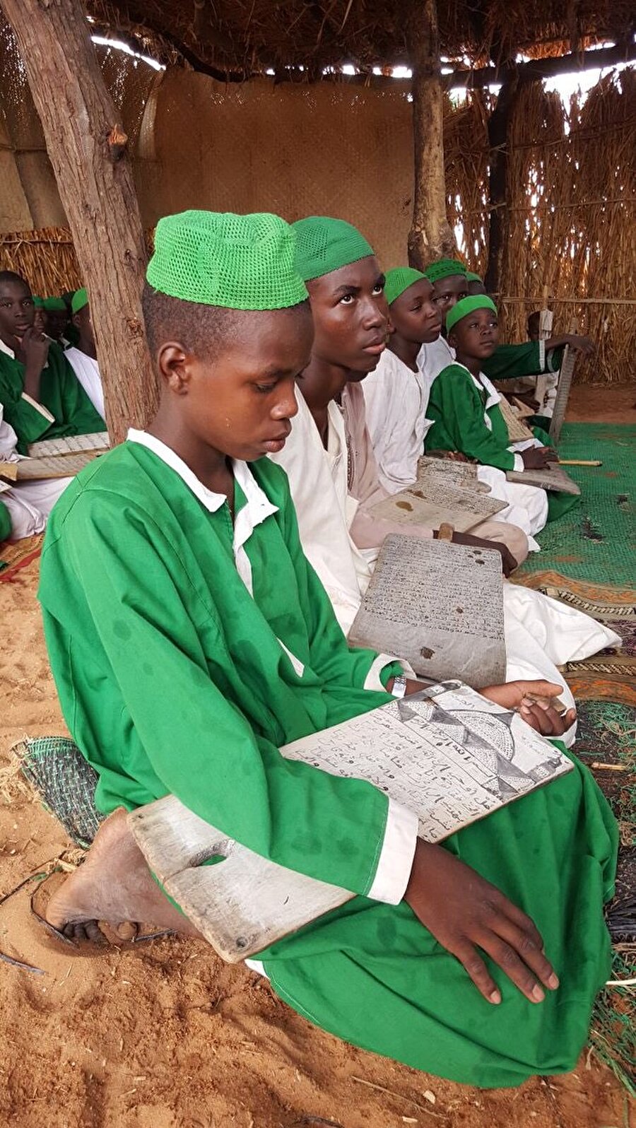 Sudan'ın Darfur bölgesindeki bir medresede öğrenciler tahta levhalarıyla eğitim görüyor.