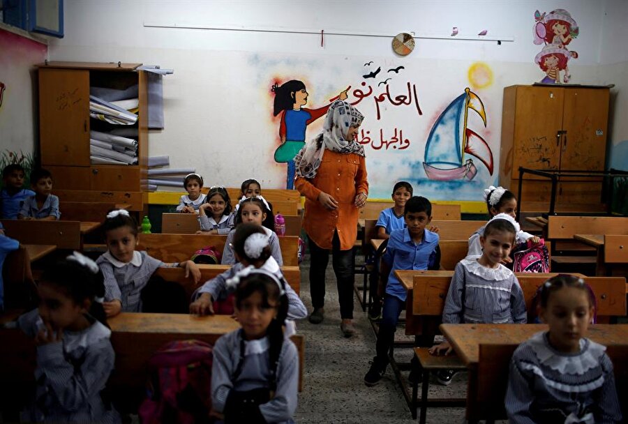 Gazzeli öğrenciler, ilk dersleri için sınıflarındaki yerlerini aldı. (Duvardaki yazı: İlim nurdur, cehalet karanlıktır.) (Mohammed Salem / Reuters)