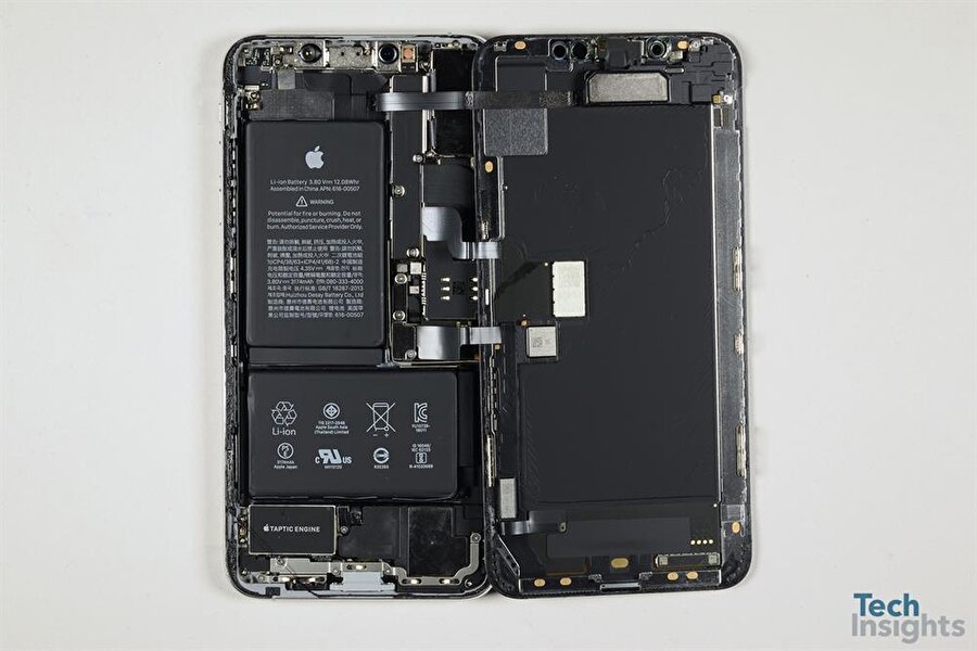 iPhone Xs Max'in arka kapağı açıldığında bu şekilde bir görüntü oluşuyor. Tahmin edilebileceği üzere en büyük parçalardan biri arka kısımdaki Apple logolu büyük batarya. Fotoğraf: TechInsights