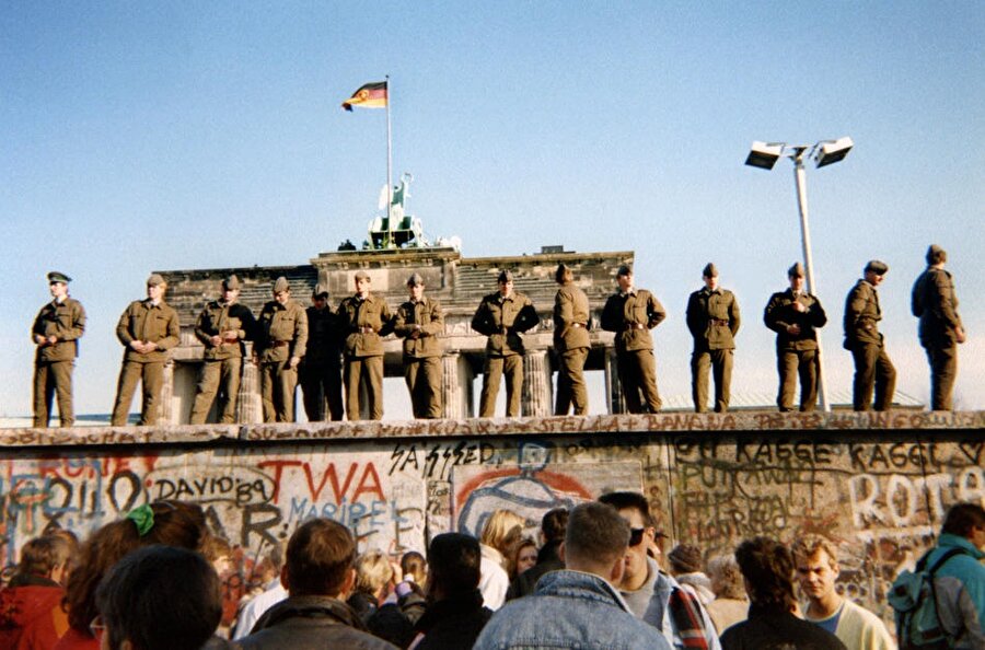 Batı Almanya'ya geçişleri engellemek için duvarın üstünde duran askerler.