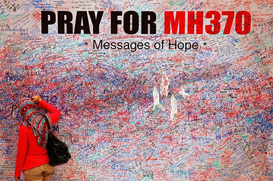 Uçakla birlikte kaybolan 239 kişi için 'MH370 İçin Dua et' yazan bir duvar.