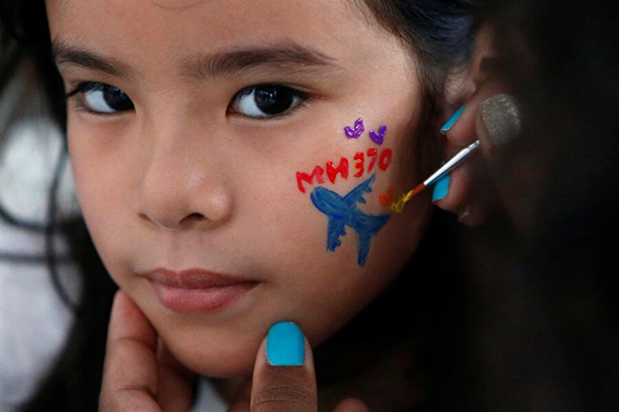 Kaybolan Malezya uçağının sefer numarasını yüzüne çizdiren küçük kız.