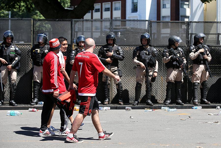 River Plate taraftarları sokakta polis kontrolünde geziyor.