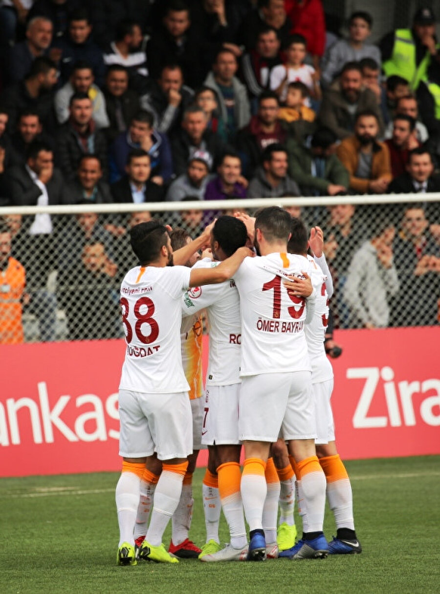 Galatasaray forması giyen genç oyuncular, golü kenetlenerek kutluyor.