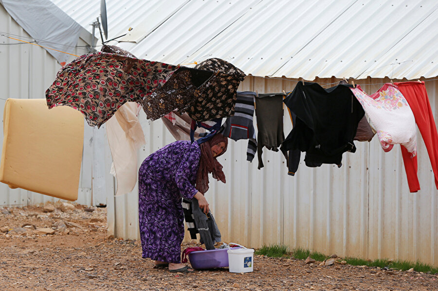 Çadır kentte bir anne, yıkadığı çamaşırlarını asıyor.