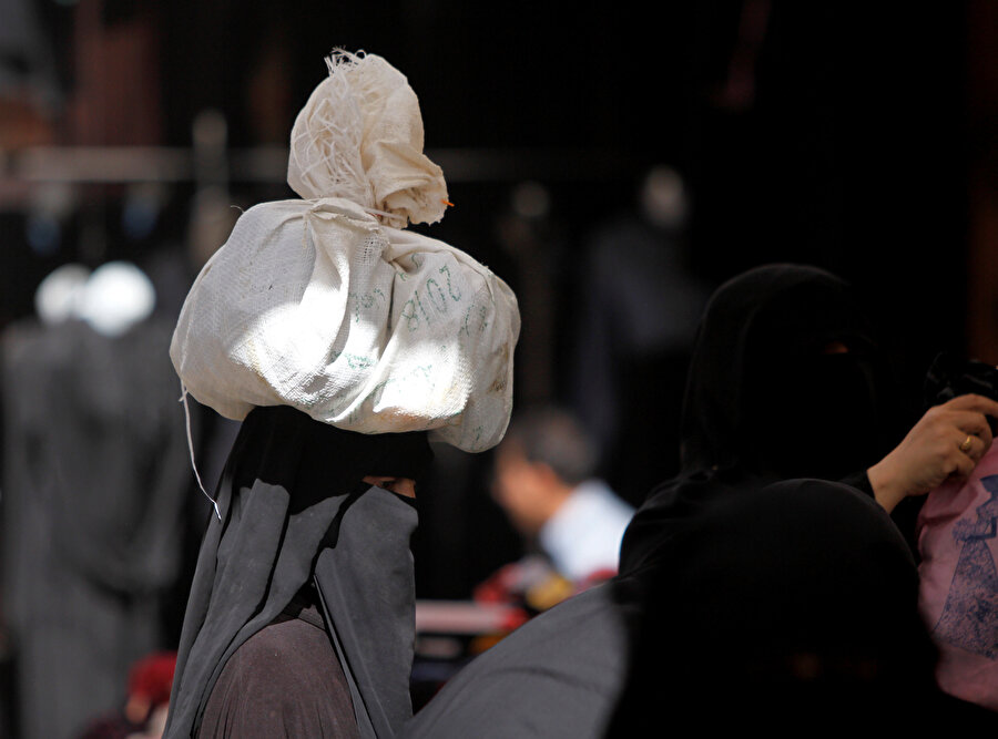 Başının üstünde yük taşıyan Yemenli bir kadın.