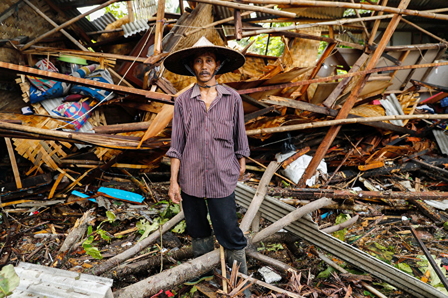 Endonezyalı bir vatandaş yıkılan evinin önünde duruyor.