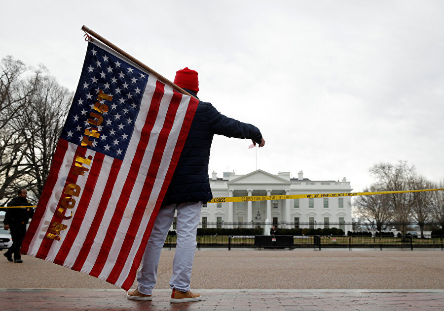Beyaz Saray'ın önünde ABD bayrağını taşıyan bir adam.