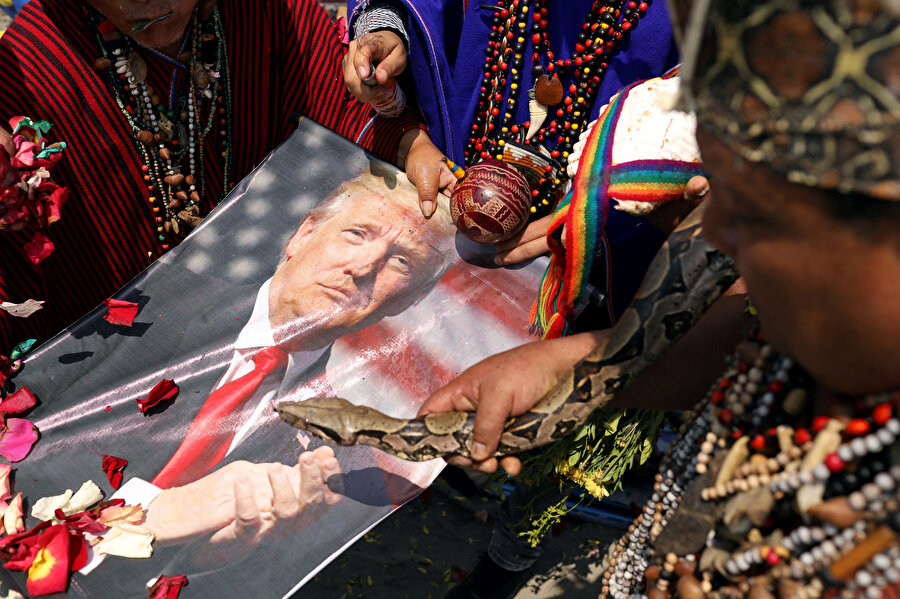 Donald Trump'ın fotoğrafına elindeki yılanla bakan bir adam. 