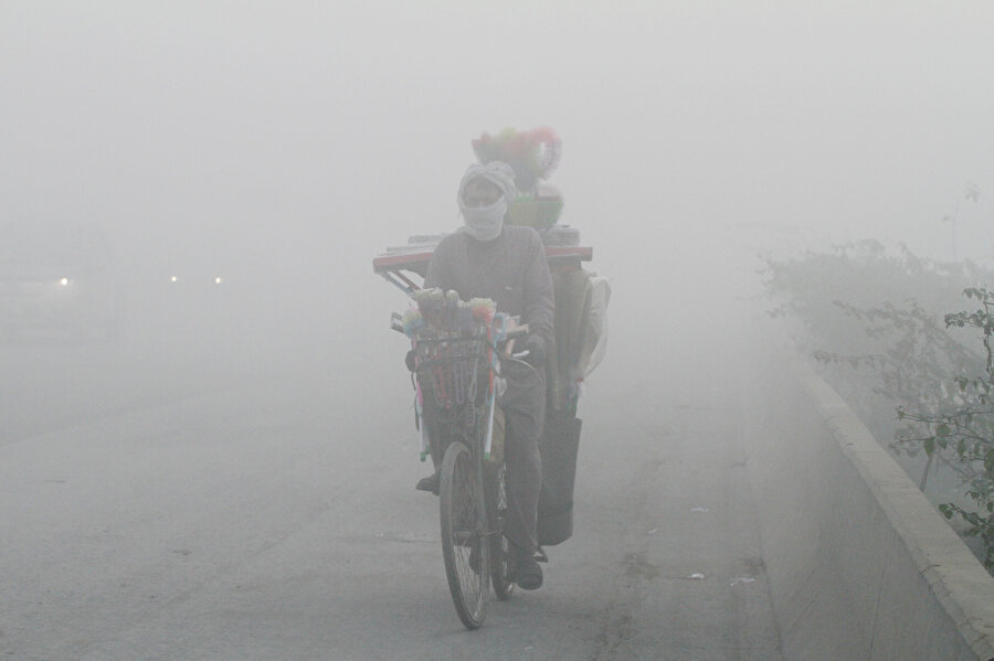 Lahor'da sisli bir sabahta bisikletiyle eşya taşıyan bir Pakistanlı.