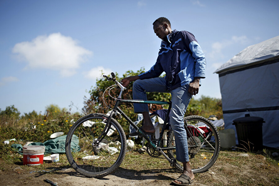 Sudanlı bir genç bisikletiyle objektife takılıyor.