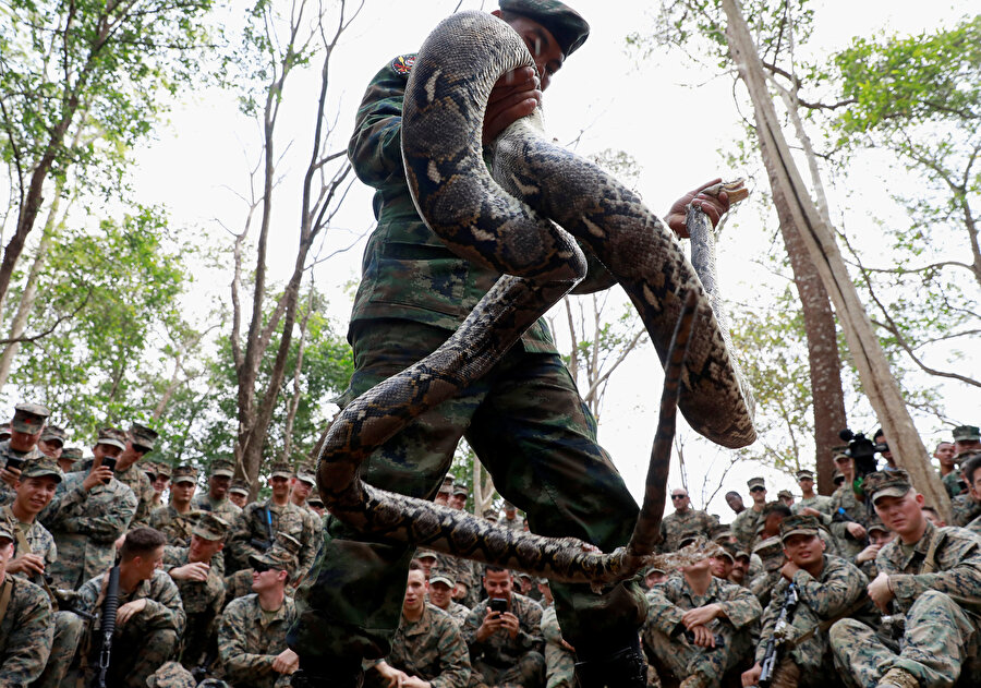 Elindeki devasa kobra yılanıyla görünen bir asker.