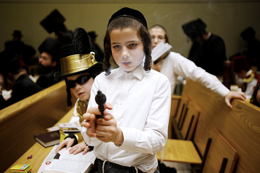Yahudi asıllı çocuk elindeki oyuncak silahla oynarken görünüyor.