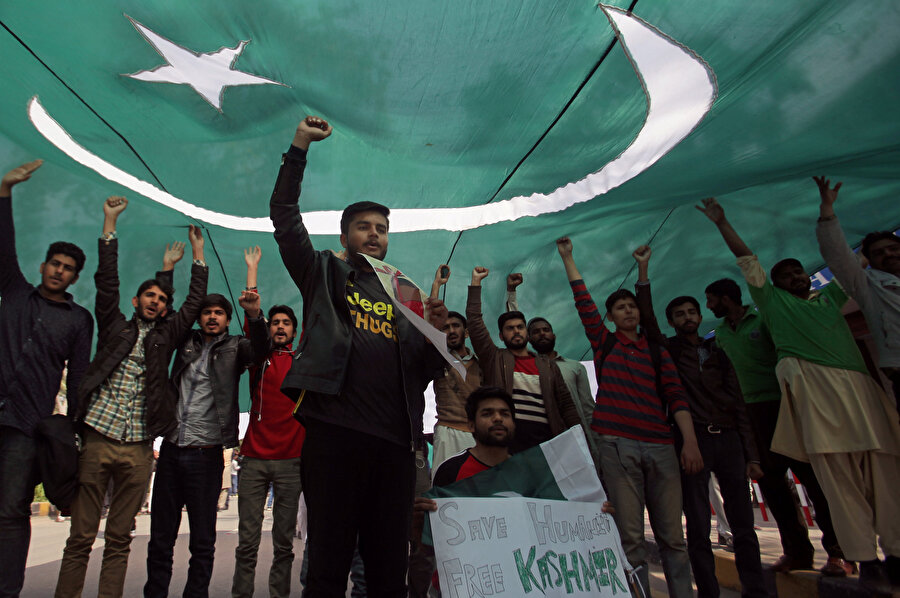 Pakistan'ın iki Hint askeri uçağını düşürdükten sonra öğrenciler ulusal bayraklarının gölgesinde slogan atarken görünüyor. 