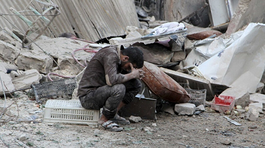 Bombardıman enkazının önünde oturan bir Halepli .
