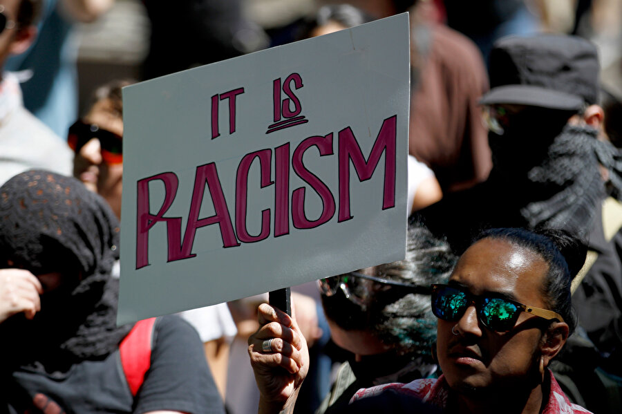 ABD'li bir vatandaş 'Bu ırkçılık' yazan pankartla görünüyor.