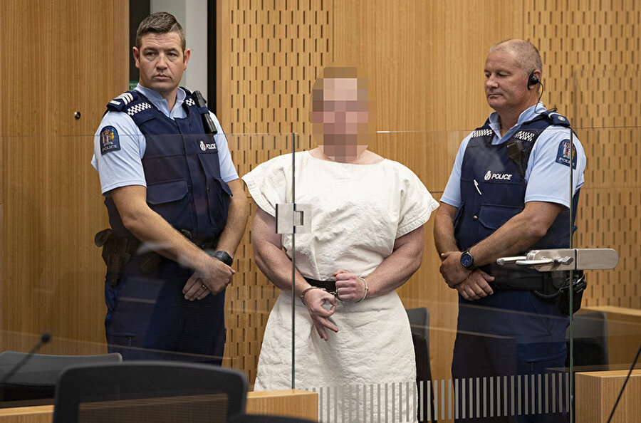 Terörist Brenton Tarrant kelepçeli elleriyle beyaz hapishane kıyafetlerinde mahkemeye çıktı. Fotoğrafı çekilen cani kameralara gülümsedi.