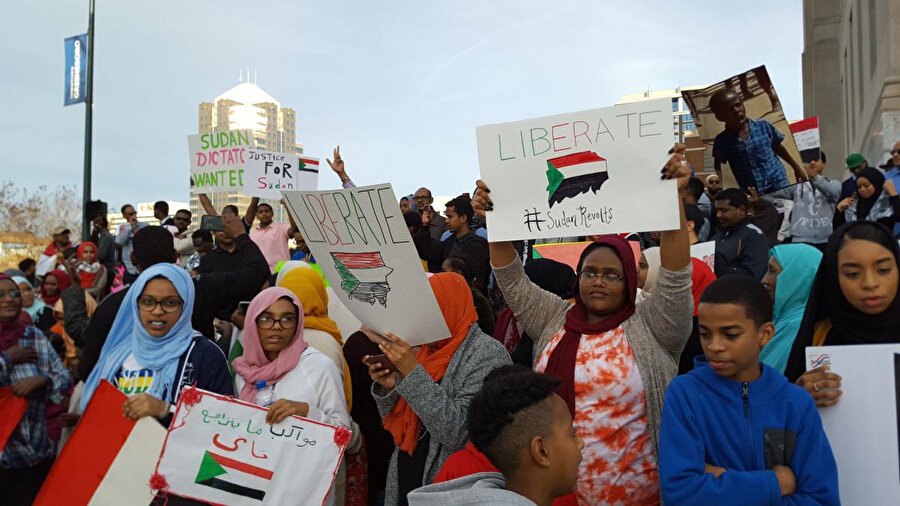 4 ay önce başlayan gösterilerde Sudanlıların üzerinde "Sudan için adalet", "Sudan ayaklanması" gibi ifadeler yazan pankartlar taşıdıkları görülüyor.